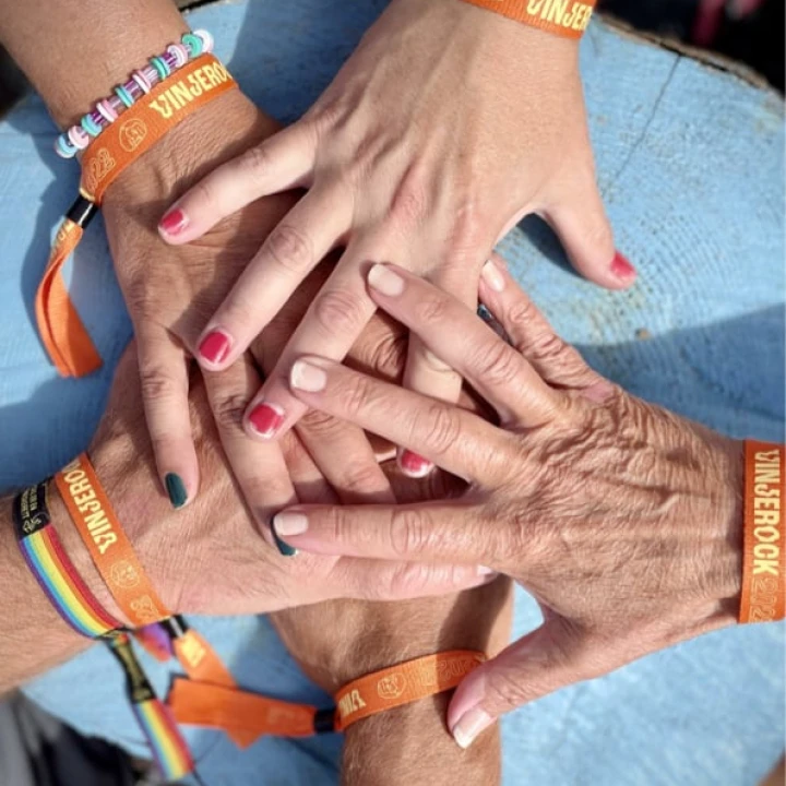 Fem hender sett ovenfra som ligger oppå hverandre fra ulike retninger. På alle armene er det "Vinjerock" armbånd og/eller pride armbånd.